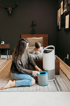 Woman beside TruSens air purifier holding HEPA filter